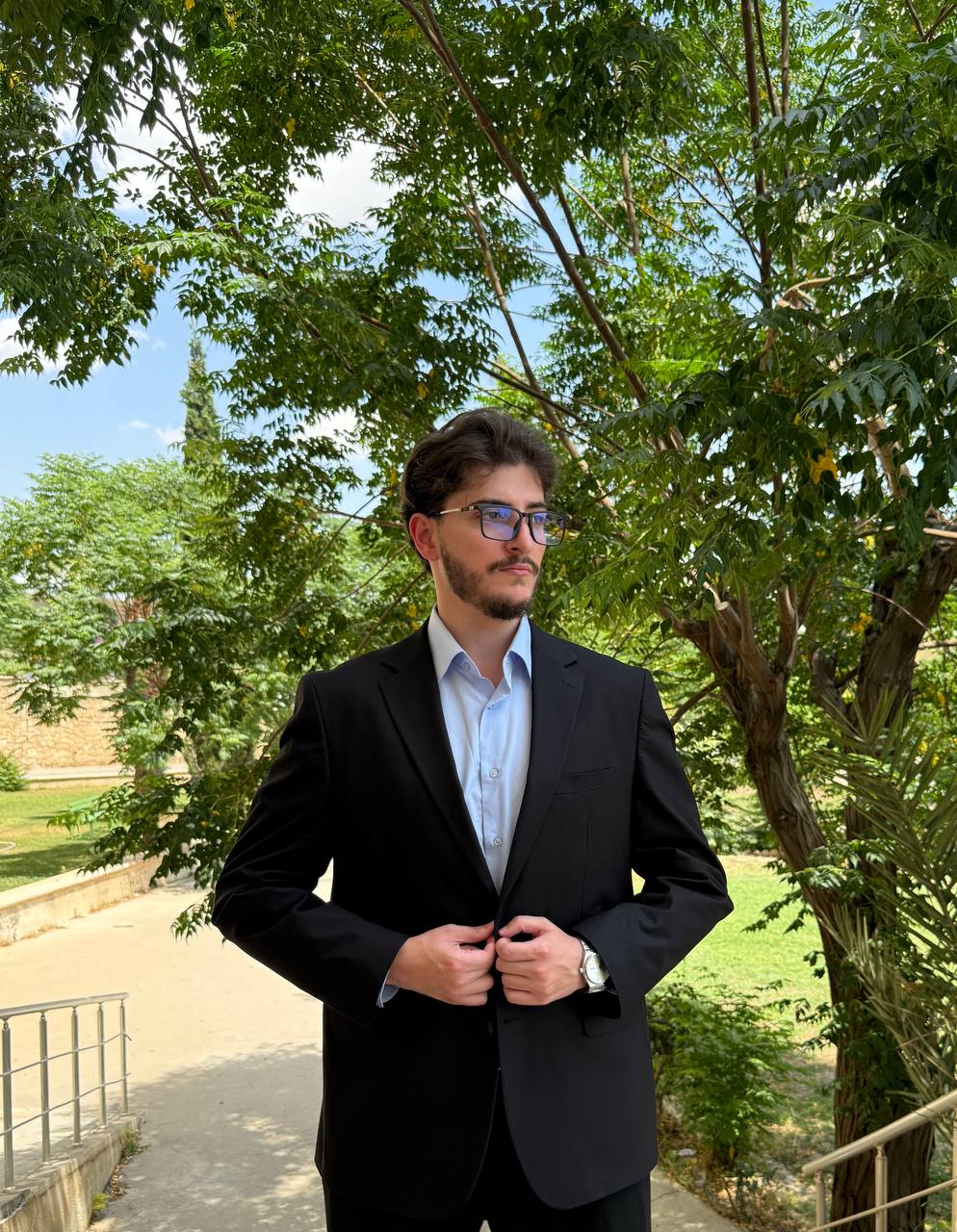Portrait of Aln Hakeem Husein in a dark suit and glasses